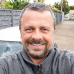 Middle aged man with grey shirt smiling taking a selfie